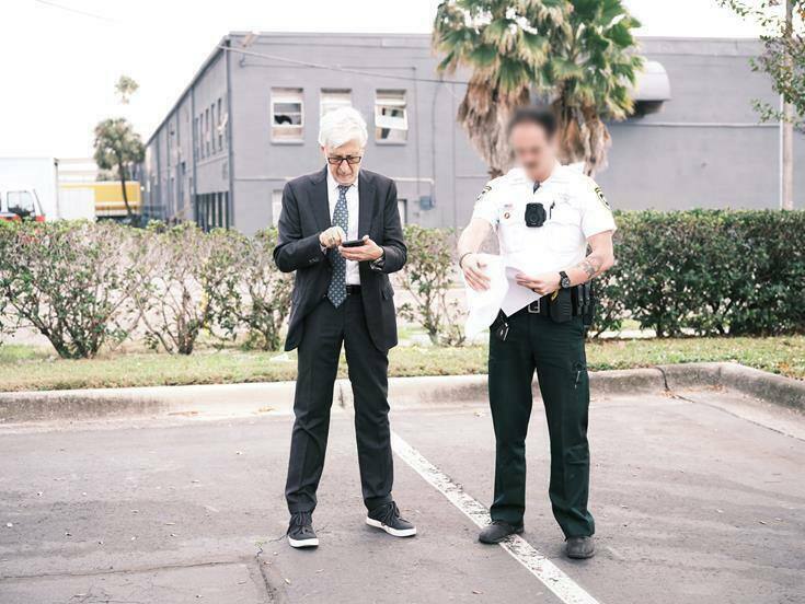 Milton Springut of Moses & Singer LLP and a police officer consult the warrant which allows L-Acoustics to enter Se7ven Sounds Music, Inc. to confiscate counterfeit L-Acoustics loudspeakers